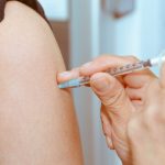 a person receiving a meningitis vaccine injection from a healthcare professional using a syringe