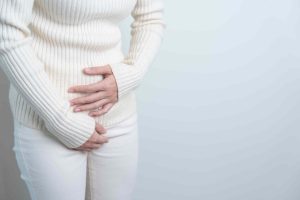 woman holding her lower abdomen frequent uti symptoms in women